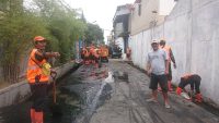 Puluhan Anggota PPSU  Wilayah Kelurahan Kamal Bersihkan Lumpur Di Saluran Air Yang Tersumbat